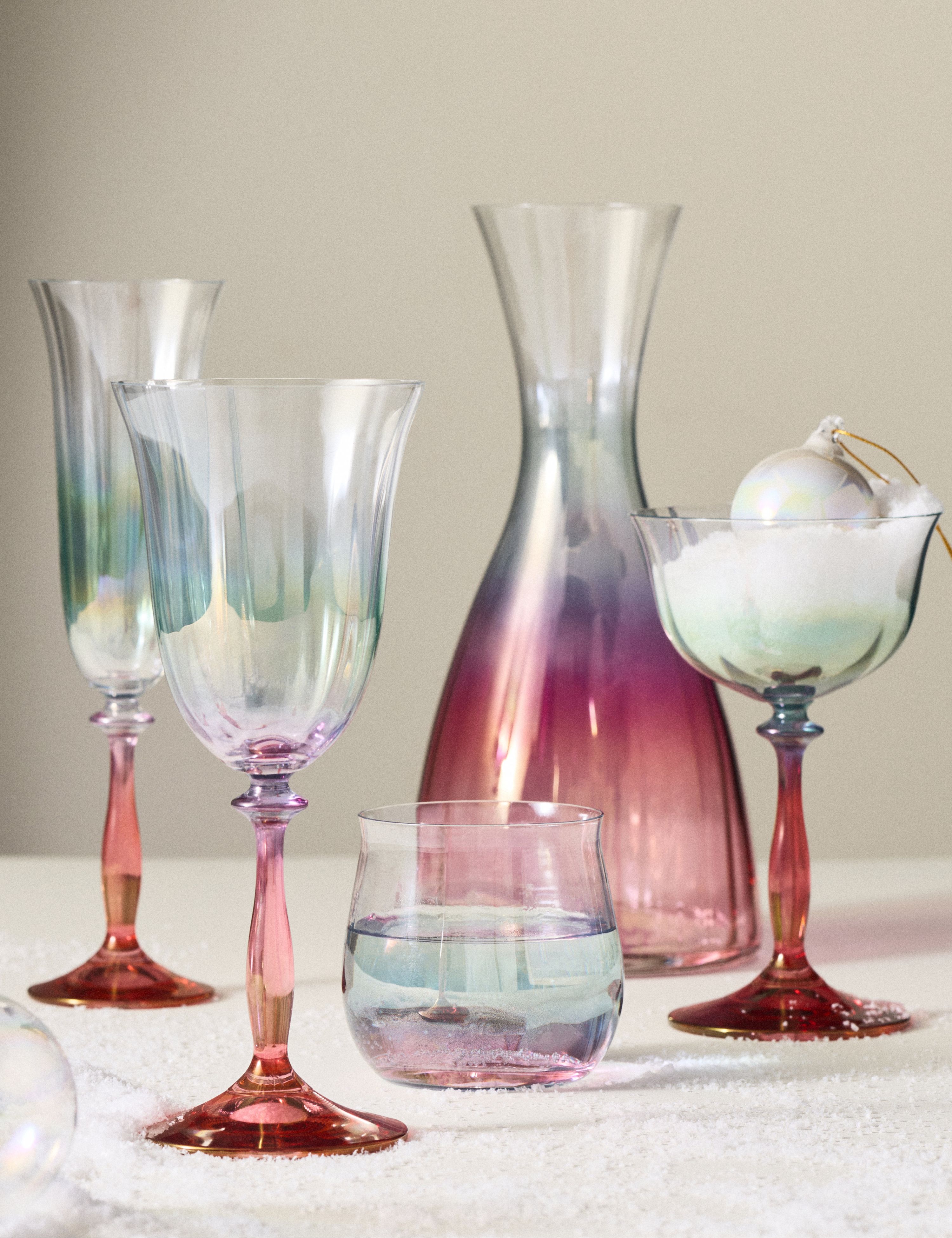 Anthropologie x New York City Ballet ombre red-to-purple-to-blue crystal stemware line up, including champagne flutes, coupes, a water glass, and a decanter