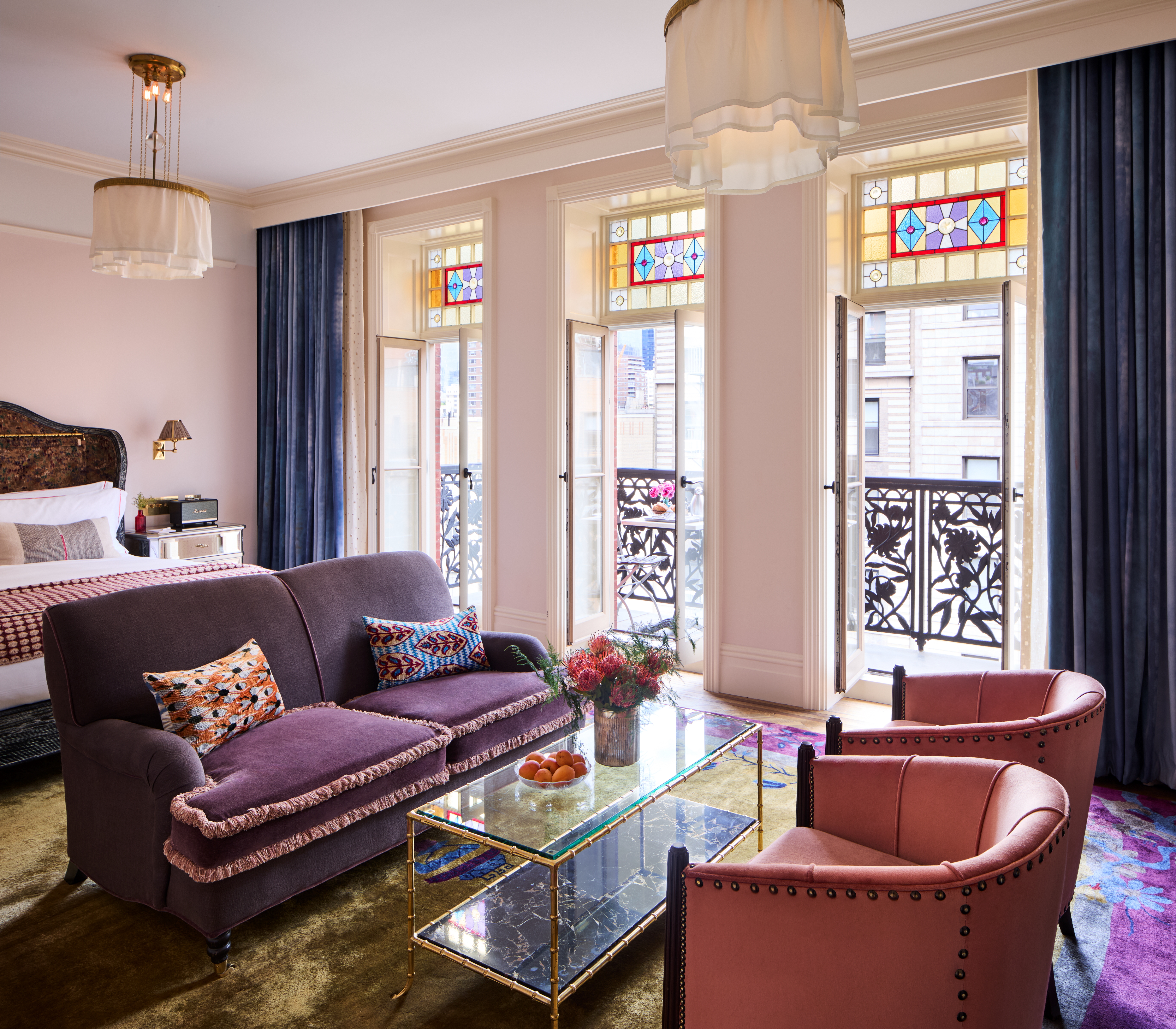 A photo of a hotel suite with a purple couch and stained glass window