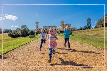 Children running towards the camera with a stately home in the background