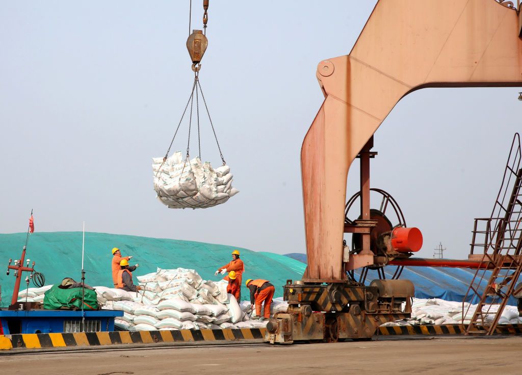 Chinese workers unload bags of soybean meal