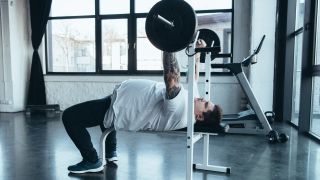 Man performing bench press with barbell in gym