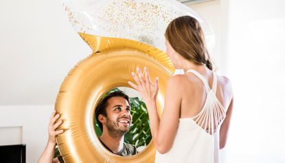 Smiling man looking at girlfriend through large inflatble ring at home - stock photo
