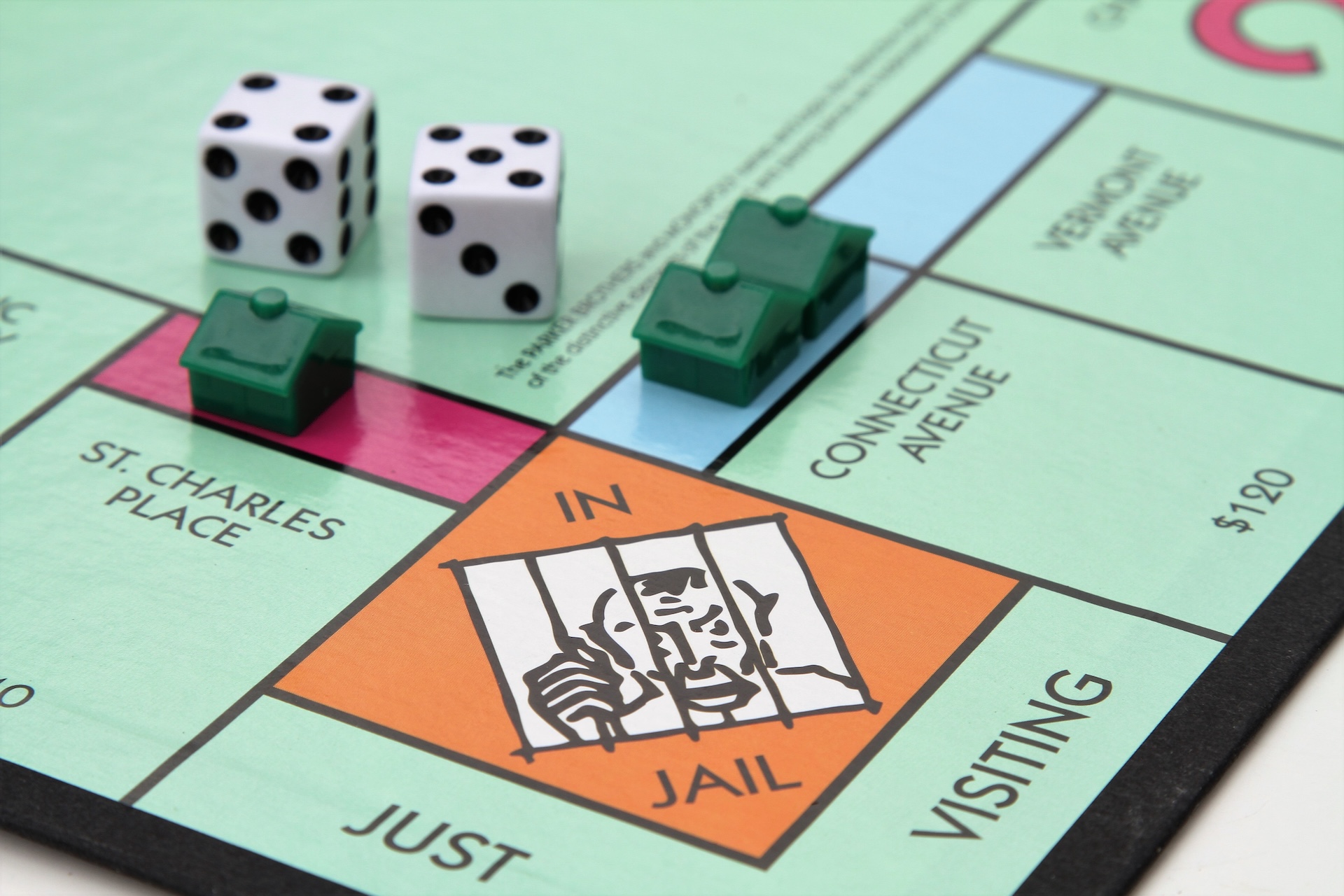 A partial view of the Monopoly game board showing the Jail space. Dice and several houses are also placed near the Jail space.