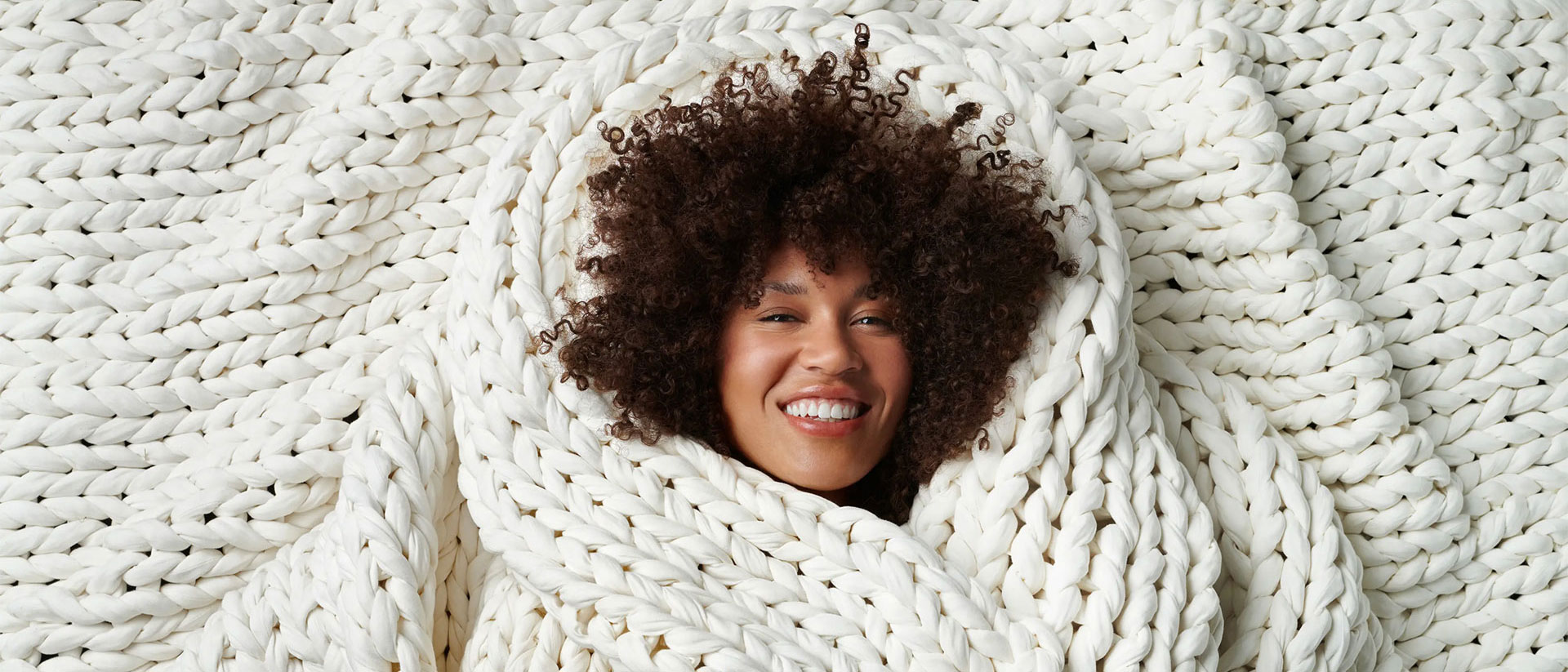 A woman wrapped in a Bearaby weighted blanket