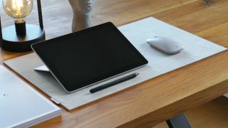A Surface device, pen, and mouse sitting on a desk.