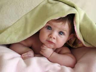 A cute baby under a blanket.