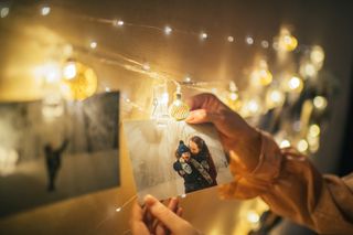 A woman attaches a polaroid to string bulbs