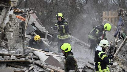 Rescuers clear debris of homes destroyed in a missile attack on the outskirts of Kyiv on 29 December