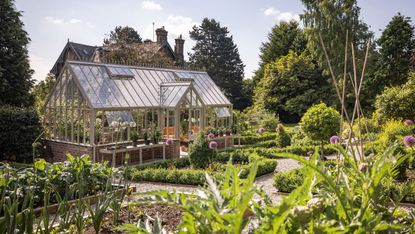 Hartley Botanic Grand Lodge greenhouse design in a country garden surrounded by vegetables and flowers 