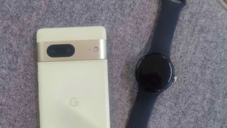 Google Pixel 7 und Google Pixel Watch nebeneinander auf einem Tisch
