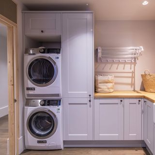 Light grey utility room with washing machine and tumble dryer stacked on top of each other.