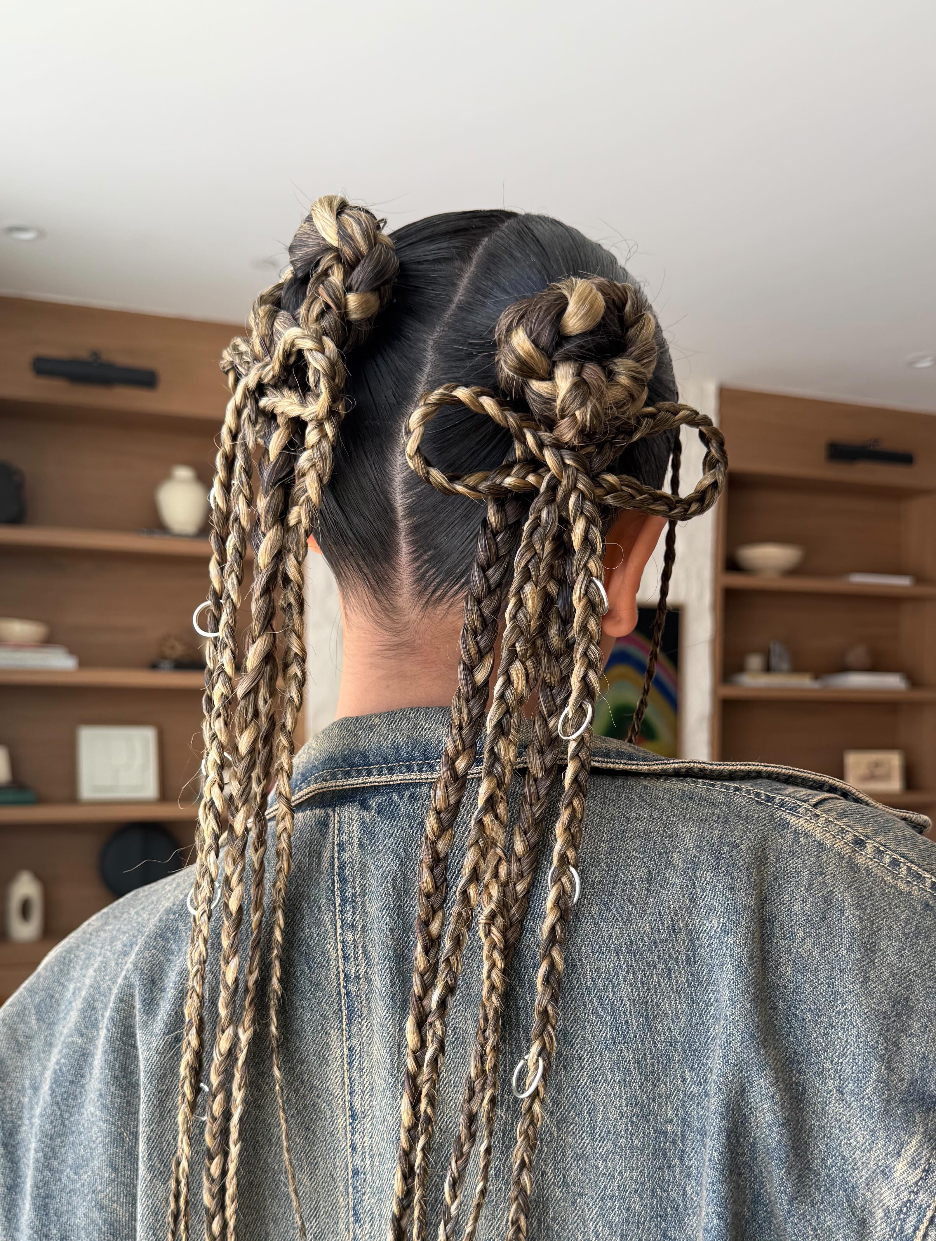 Desi Perkins wears extra small braids in a bun and bow by Justine Marjan