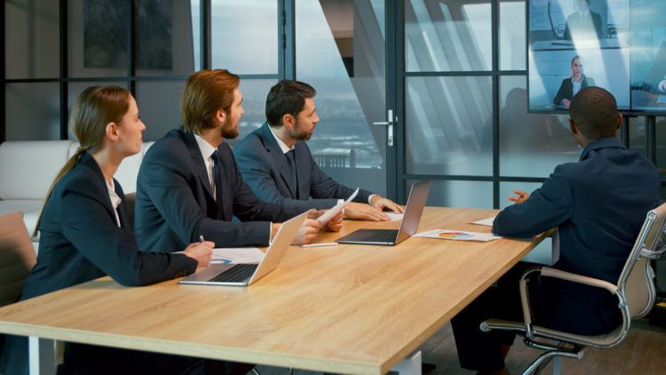 A videoconference room with three people enjoying meeting equity thanks to a collaboration from Kramer and Jabra.