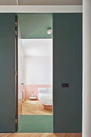 A bedroom with teal doors, and a pink band of paint along the wall