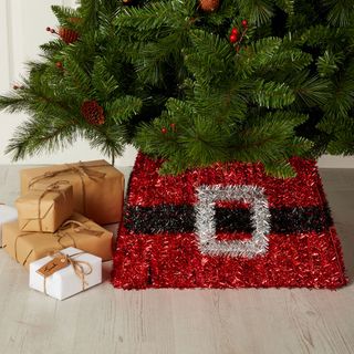 Santa's belt Christmas tree skirt in red tinsel beneath green Christmas tree with wrapped presents