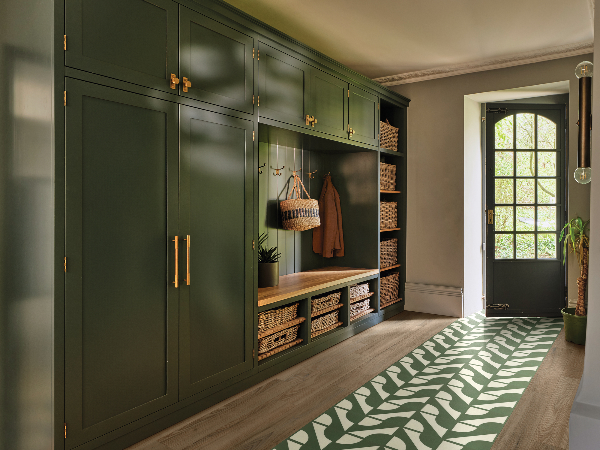 A hallway with engineered wood flooring an a green and white geometric pattern inlay