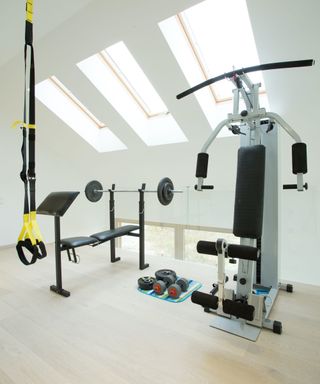A home gym with blond wood flooring and skylights
