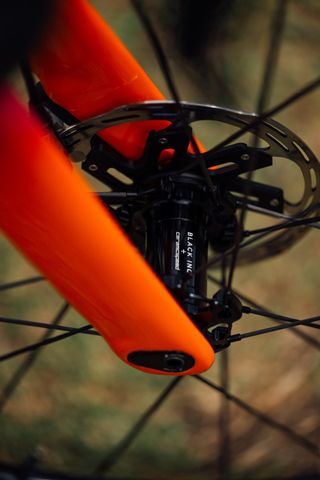 A Black Inc front hub bolted into orange Factor fork legs