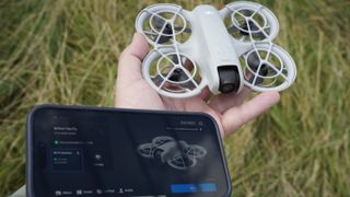 DJI Neo drone and iPhone with the DJI Fly app in a field