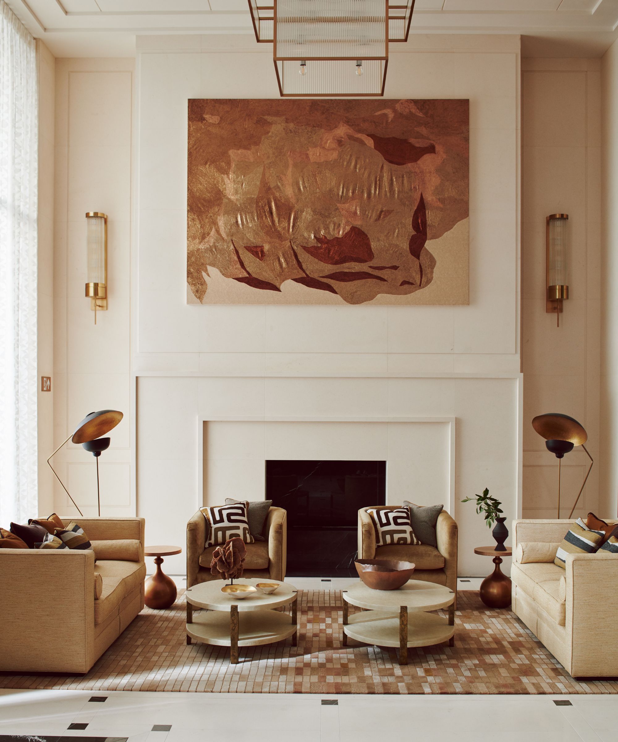 Symmetrically arranged, elegant living room with neutral-toned seating, a central fireplace, and a large, textured copper-toned artwork above the mantel