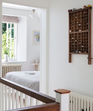 white painted landing with pigeon hole wooden wall storage and view through to bedroom