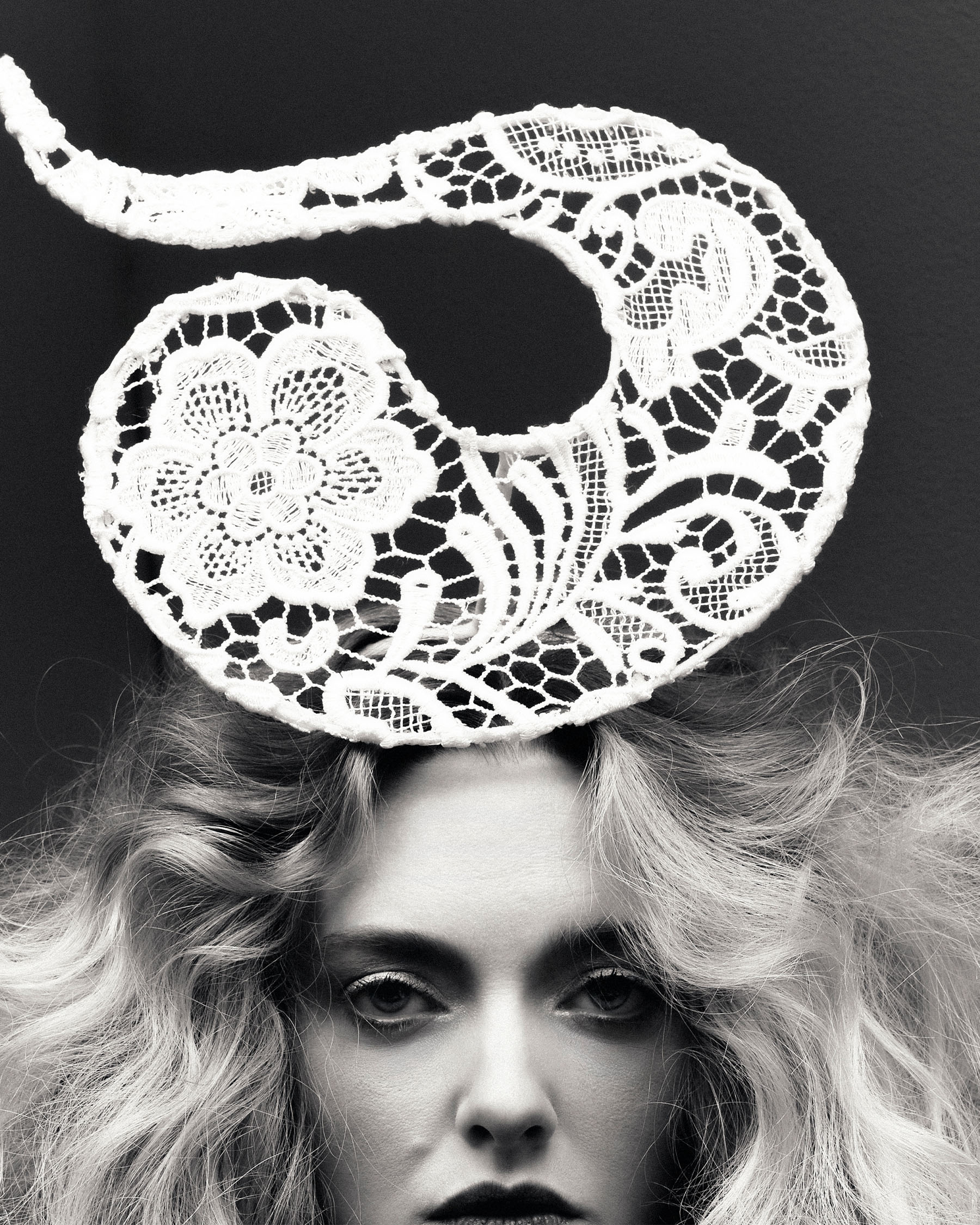 Amanda Seyfried for Who What Wear&#039;s December cover story. She is photographed from the mouth up wearing a fascinator-like white crochet hat. The image is in black and white.