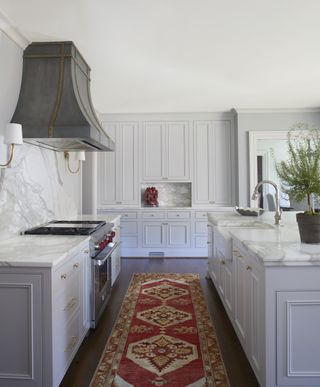 A kitchen with a runner and an island with a sink