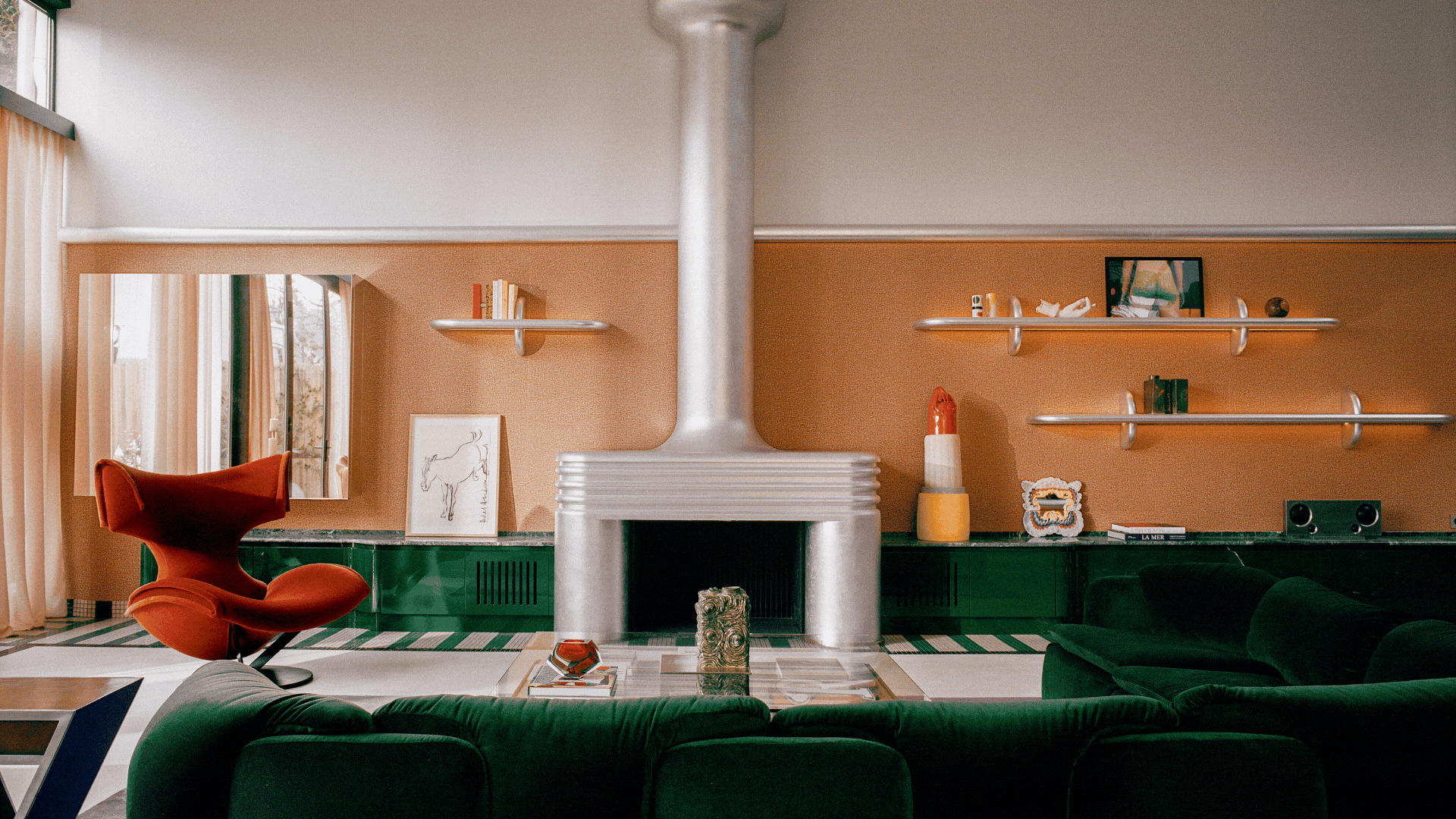 Rotating GIF of three Space Age-inspired rooms that have lots of curved, lacquered furniture throughout the space. The color palette is mostly silver, dark green, and red.