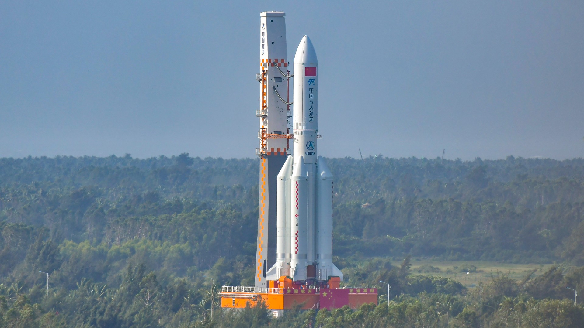 a chinese rocket on the launch pad with forest in behind