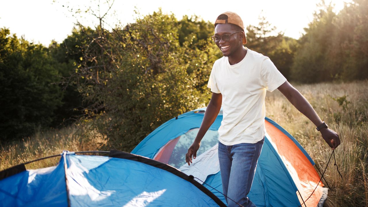 Young casually clothed man setting up tent