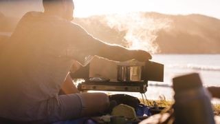best camping stoves: A man preparing a meal on a stove