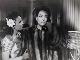 joan crawford wears a fur coat and talks on the phone in the movie mildred pierce