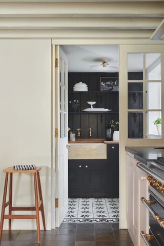black laundry room seen though the door of the kitchen Shaker style with patterned floor tiles