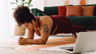 Woman performs plank core exercise at home