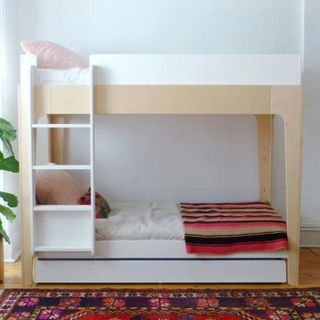 Oeuf Perch Bunk Bed in kids room with rug and colourful bedding beside plant