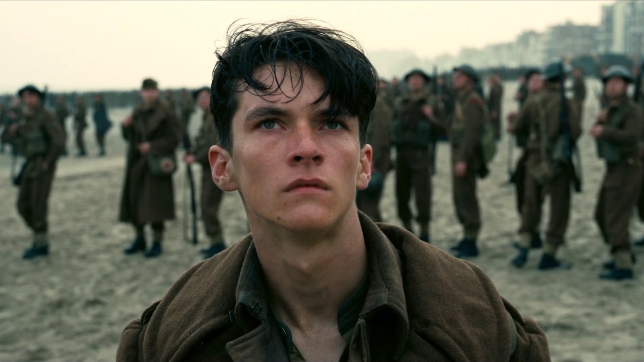 A still from the movie Dunkirk in which a soldier stood on the beach is staring into the distance.