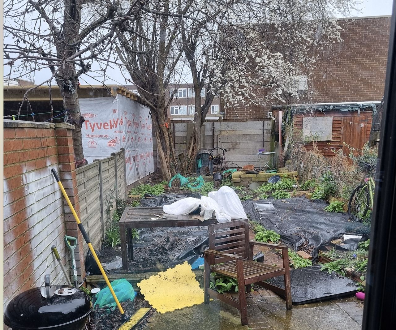 The before shot of a small urban garden with lots of clutter and no proper fence