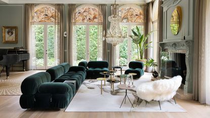 living room with green sectional and white fluffy chair and grand piano and arched windows