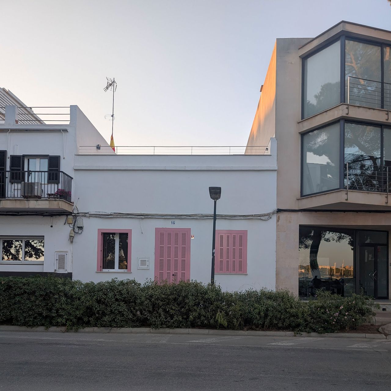 Terraced buildings on street, one painted white with pink door and shutters