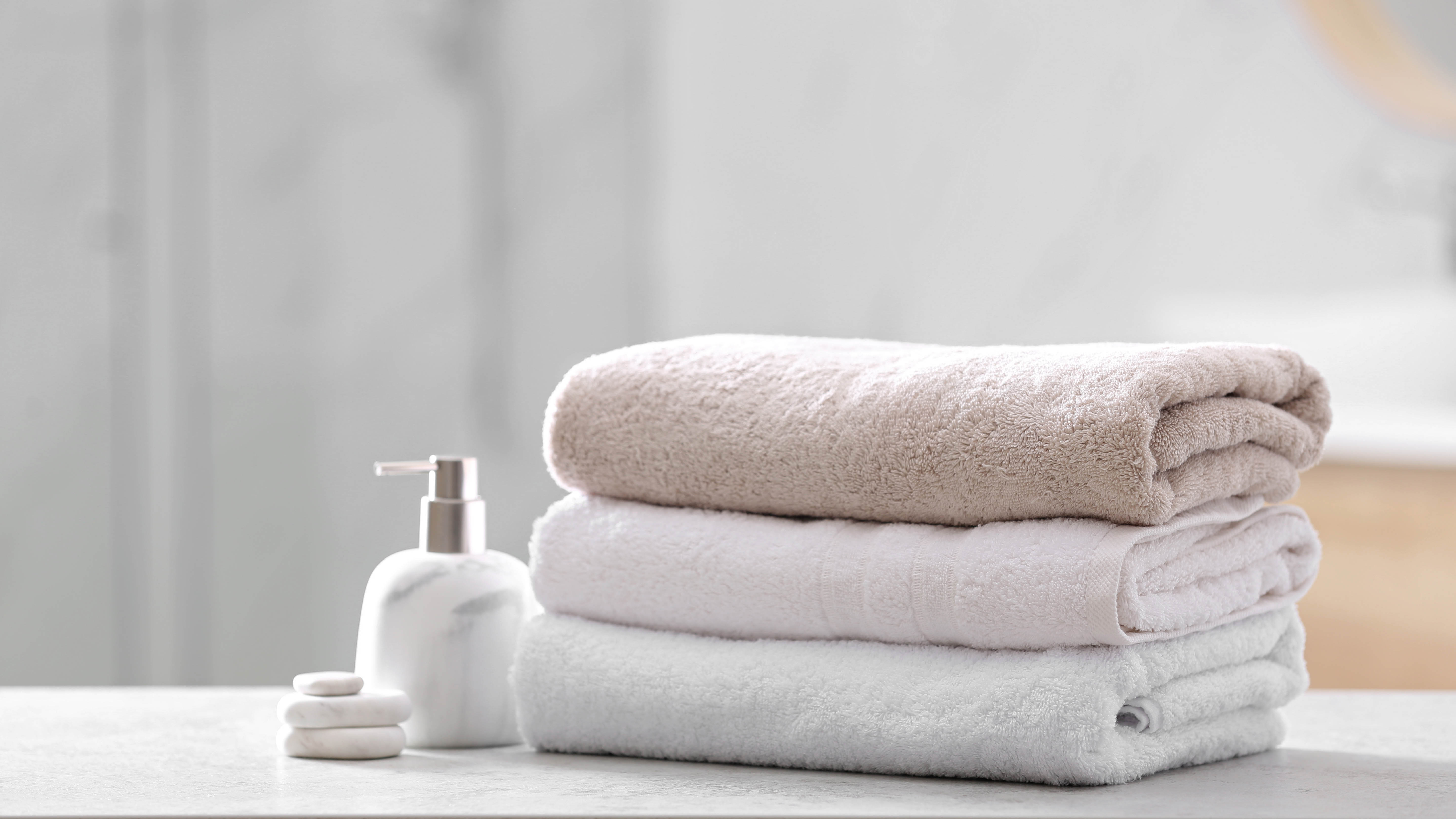 Три полотенца сложены друг на друга рядом с дозатором мыла.