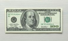 One hundred dollar bill note on white wood grain background