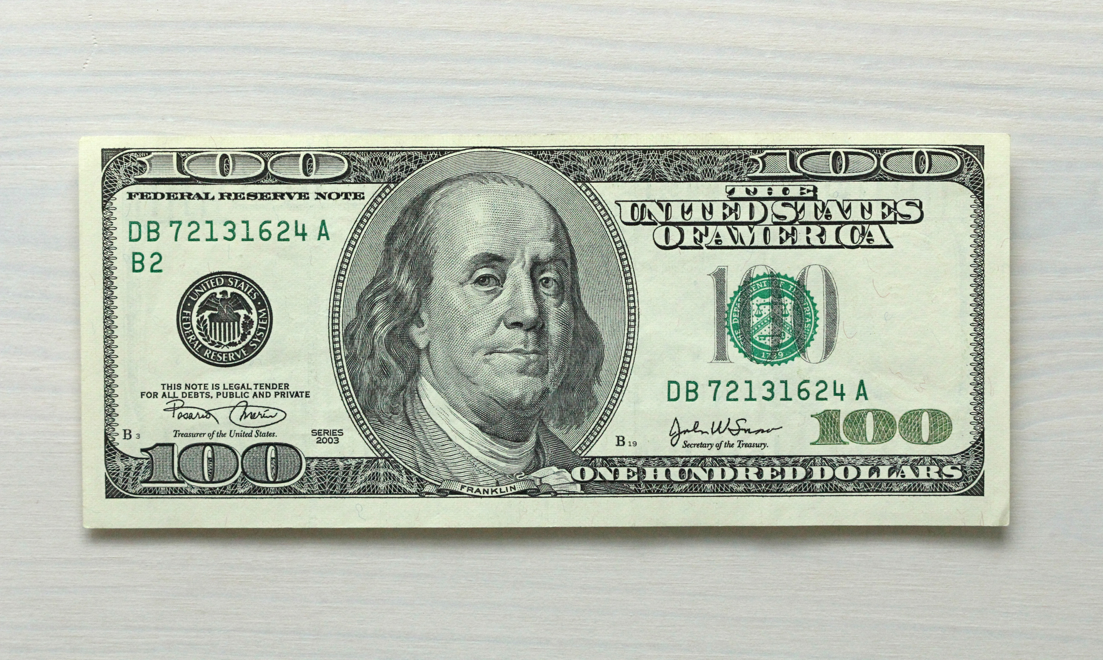 One hundred dollar bill note on white wood grain background