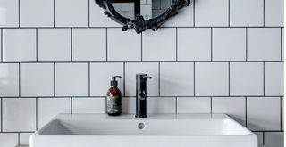 Monochrome bathroom sink area with white metro tiles with black grout