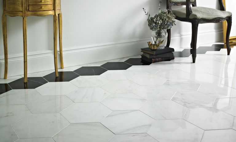 Polished hexagonally shaped marble floor tiles in hallway in white with accent black border and gilded side table