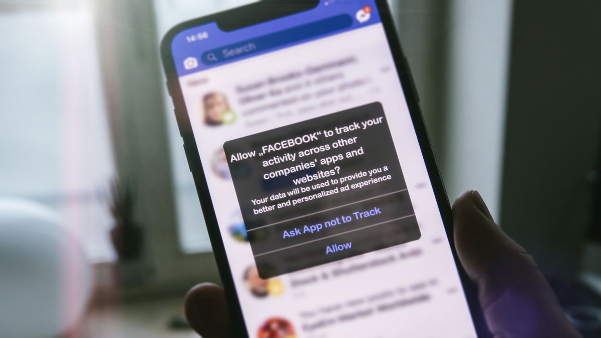 A hand holding an iPhone which displays a Facebook app notification requesting permission from users to track their activity across other apps
