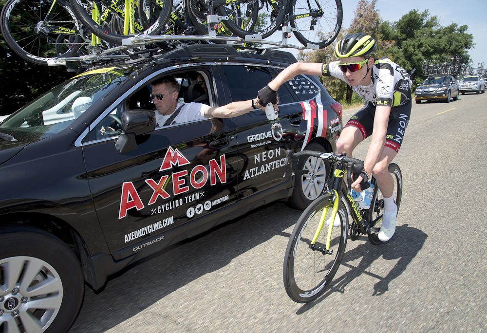 Axel Merckx drives the Axeon car while Logan Owen gets a bottle