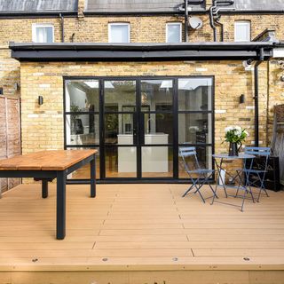 single storey terraced house extension with black Belgian doors leading to a wooden deck