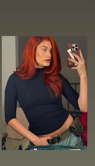 A photo of Hailey Bieber sporting bright red hair as part of her Kim Possible Halloween costume.