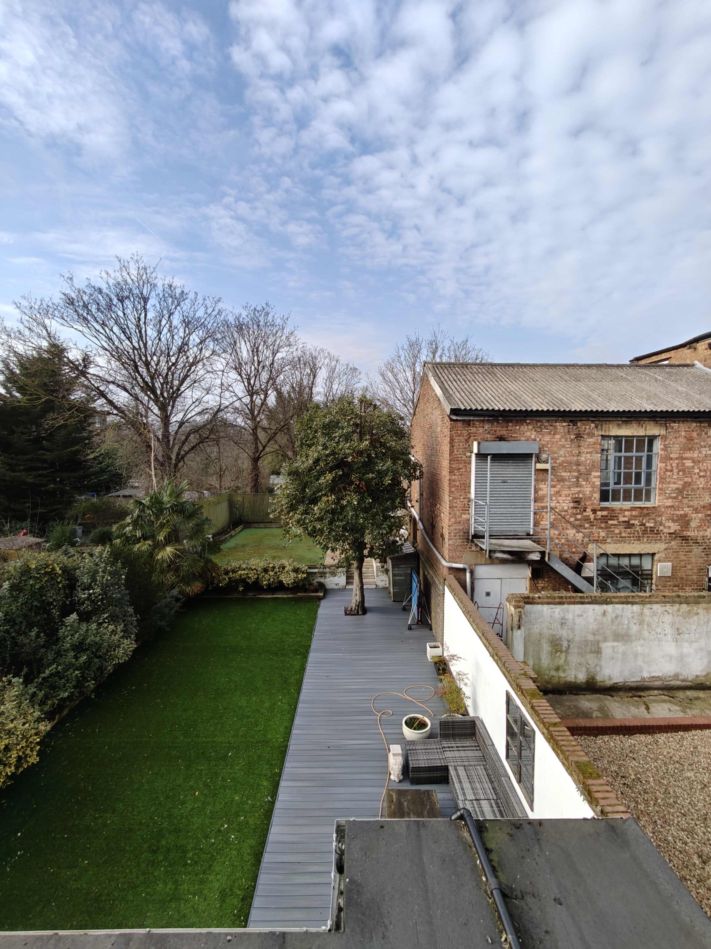 Long garden next to a brick warehouse 