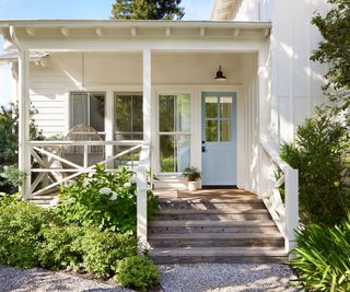covered front porch with wooden steps leading down to a lawn and path